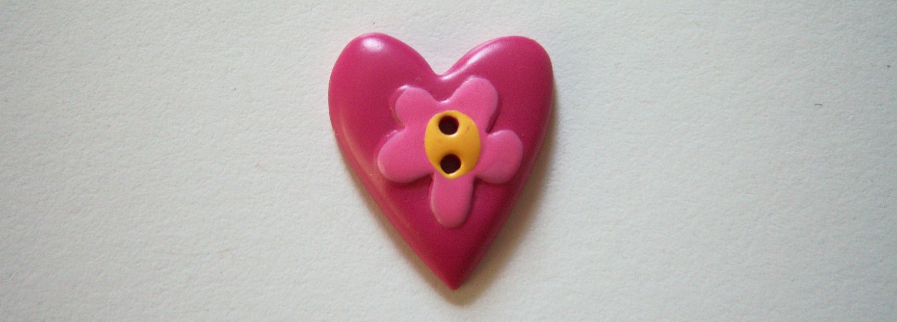 JHB Elongated rasberry heart/pink center daisy with yellow center on 2 holes 3/4" poly resin button.